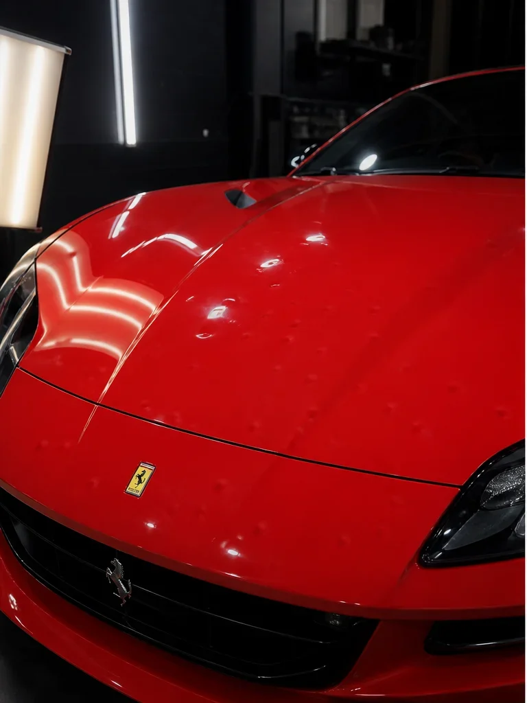 Red Ferrari hood before hail damage repair